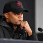Vincent Kompany in een donkere jas en pet tijdens een rustig mediamoment.