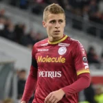 Een speler van Zulte Waregem in een bordeaux shirt wijst op het veld.