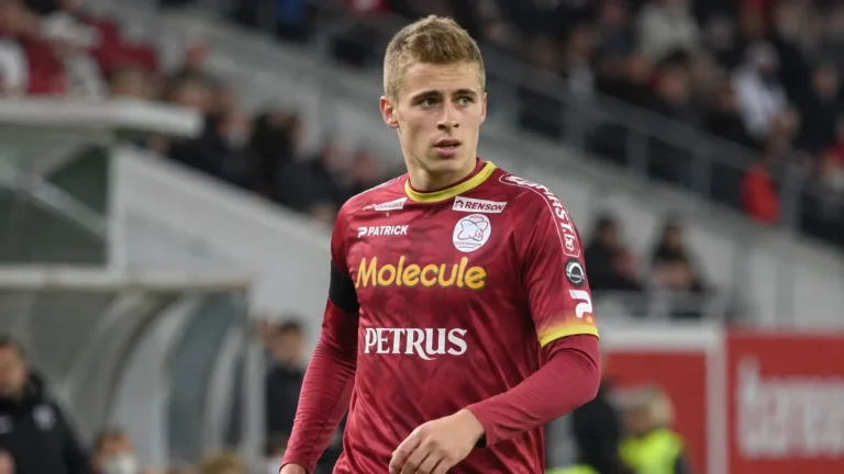 Een speler van Zulte Waregem in een bordeaux shirt wijst op het veld.