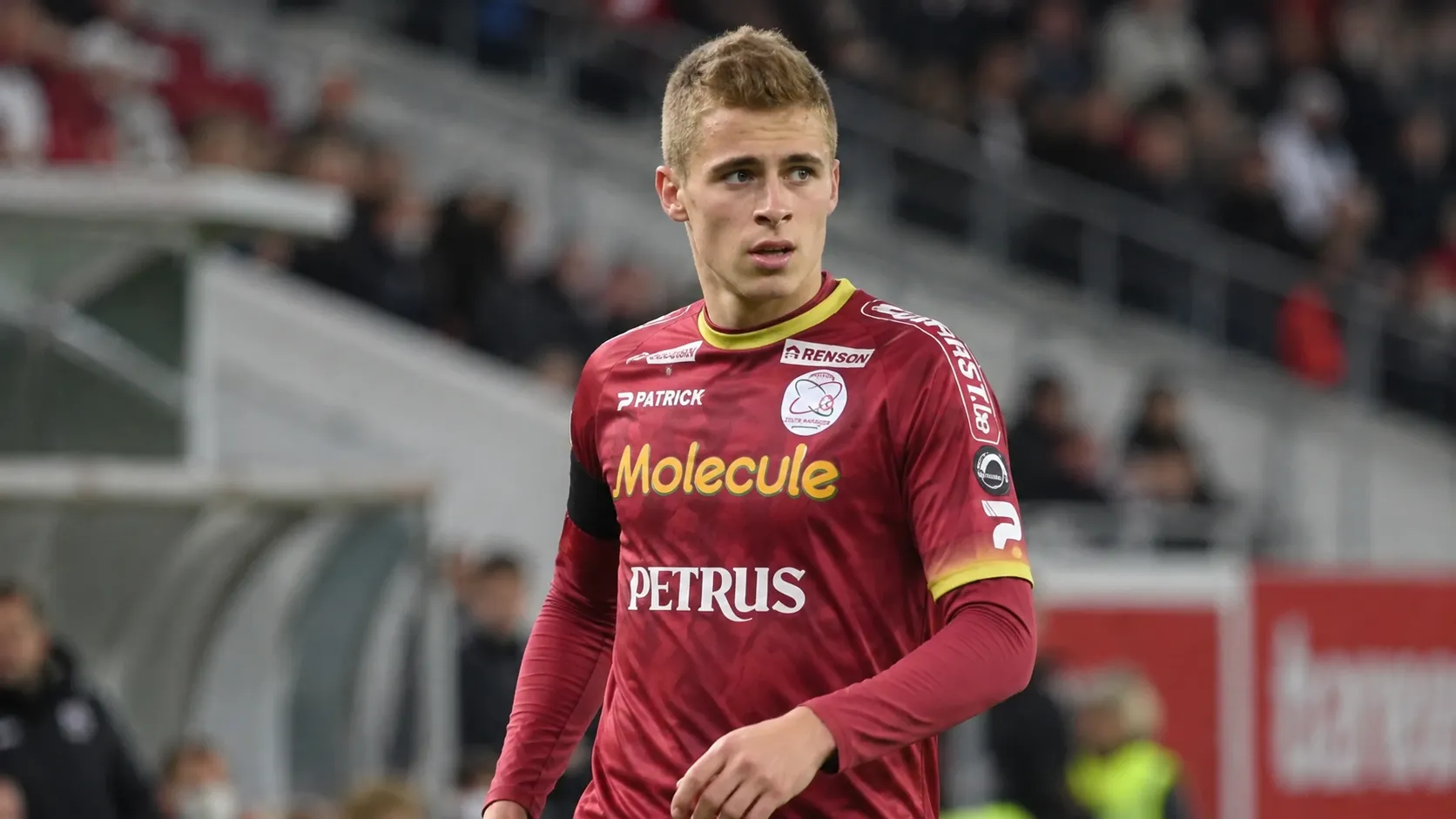 Een speler van Zulte Waregem in een bordeaux shirt wijst op het veld.
