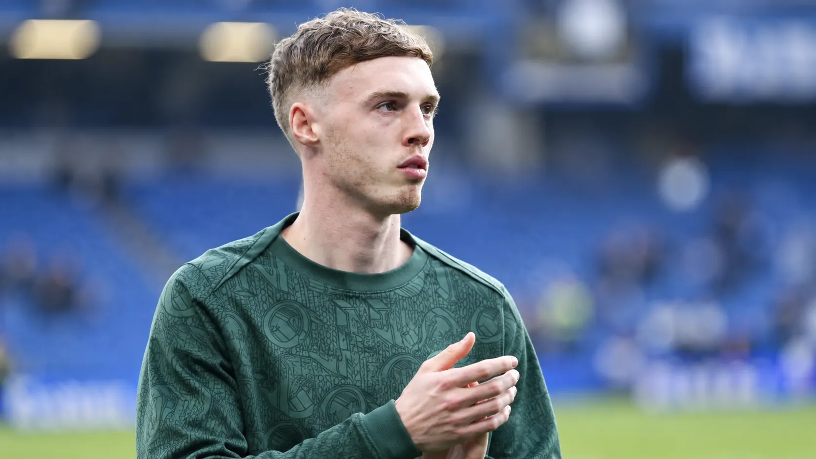 Cole Palmer in een groen trainingsbovenstuk aan de rand van een voetbalveld.