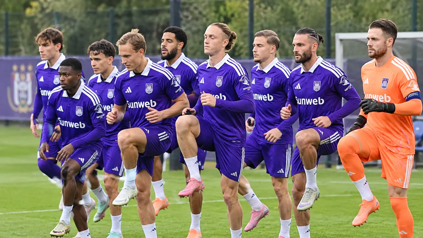 Een groep spelers van RSC Anderlecht warmt op het veld op in paarse wedstrijdtenues.