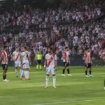Een groep voetballers wacht op het veld tijdens een onderbroken wedstrijd.