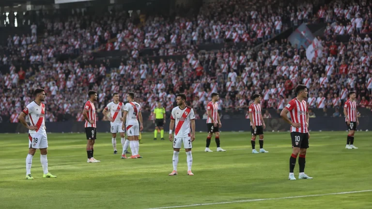 Een groep voetballers wacht op het veld tijdens een onderbroken wedstrijd.