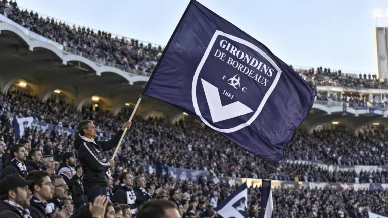 Supporters van Girondins de Bordeaux met een grote paarse clubvlag in het stadion.