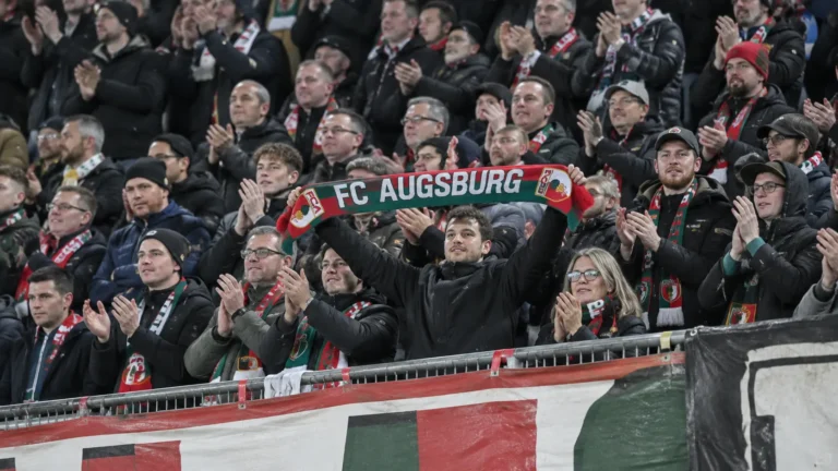 Collectieve supporters van Augsburg vieren in de thuistribune met een clubsjaal.