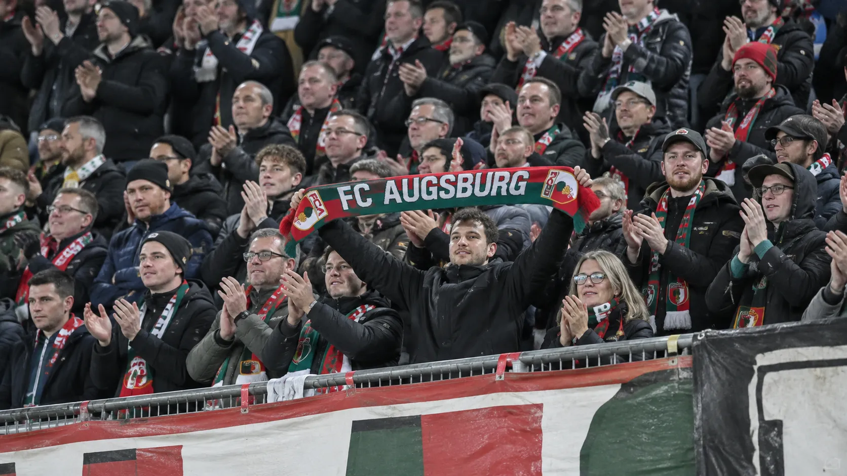 Collectieve supporters van Augsburg vieren in de thuistribune met een clubsjaal.