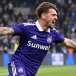 Een Anderlecht-speler in paars wedstrijdtenue tijdens een actie op het veld.