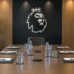 Lege formele vergaderzaal met een Premier League-embleem op een wandpaneel.