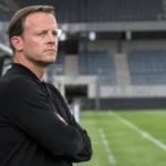 Vincent Euvrard in zwarte coachkleding aan de technische zone voor een wedstrijd.