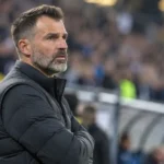 Een Club Brugge-coach in een donkere jas langs de zijlijn na de wedstrijd.