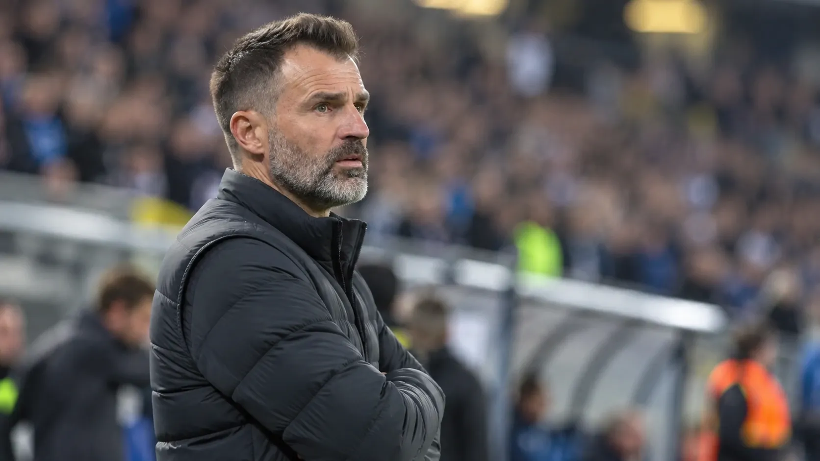Een Club Brugge-coach in een donkere jas langs de zijlijn na de wedstrijd.