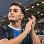 Een speler in een blauw-zwart shirt reageert na een uitwedstrijd aan de rand van het veld.