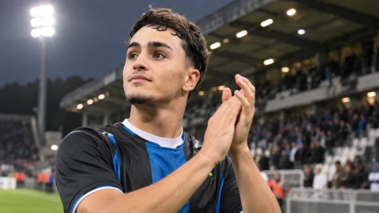 Een speler in een blauw-zwart shirt reageert na een uitwedstrijd aan de rand van het veld.