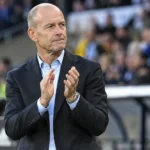 Jess Thorup kijkt geconcentreerd langs de zijlijn van een stadion.
