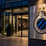 Lege ingang van een Club Brugge-clubgebouw met het embleem op een metalen naambord.