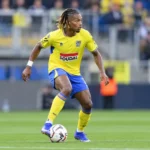 Ibrahim Fofana in het geel-blauwe tenue van Westerlo tijdens een voetbalactie op het gras.