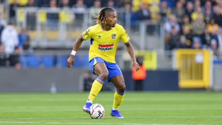 Ibrahim Fofana in het geel-blauwe tenue van Westerlo tijdens een voetbalactie op het gras.