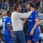 KAA Gent-spelers en een staflid begroeten elkaar na een wedstrijd langs de zijlijn.