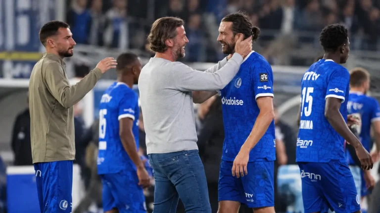 KAA Gent-spelers en een staflid begroeten elkaar na een wedstrijd langs de zijlijn.