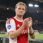 Kasper Dolberg in het rood-witte shirt van Ajax applaudisseert langs het veld.