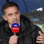 Gary Neville spreekt met een Sky Sports-microfoon vanuit een overdekte uitzendpositie naast het veld.