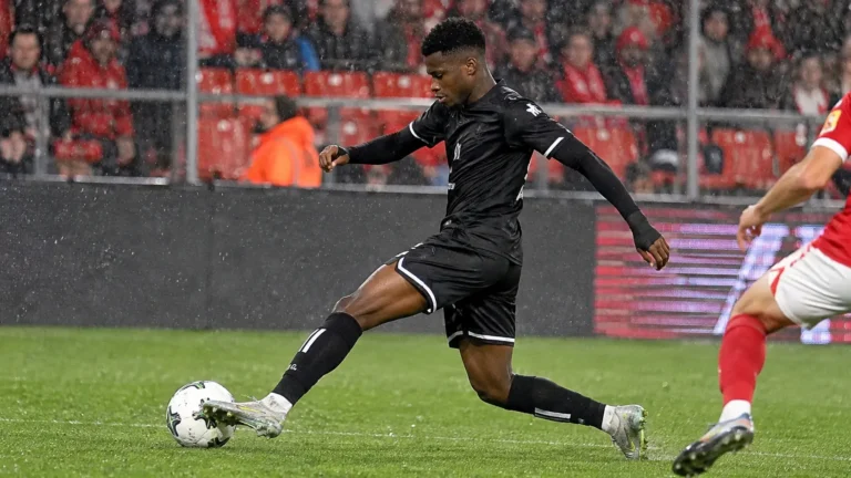 Een voetballer in een zwart wedstrijdtenue tijdens een duel in Sclessin.