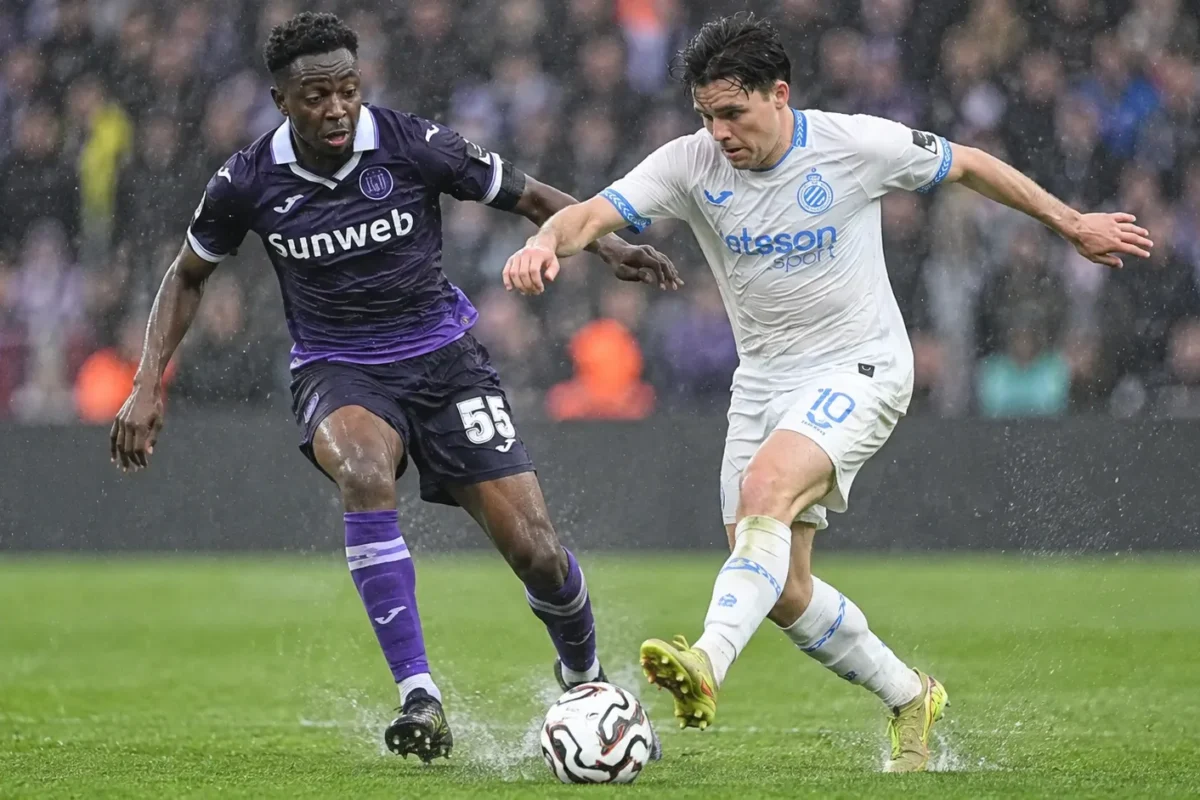 Een speler van Club Brugge en een speler van RSC Anderlecht strijden in de regen om de bal.
