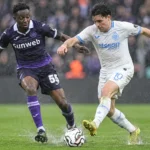 Een speler van Club Brugge en een speler van RSC Anderlecht strijden in de regen om de bal.