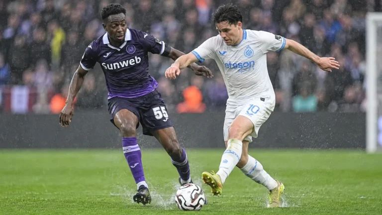 Een speler van Club Brugge en een speler van RSC Anderlecht strijden in de regen om de bal.