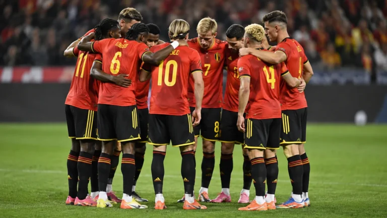 Een groep Belgische internationals vormt in rode wedstrijdshirts een hechte kring op het veld.