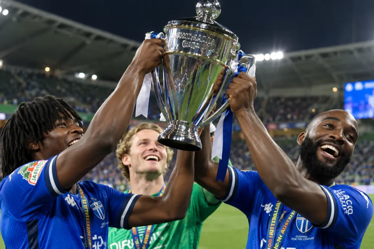 Drie voetballers van South Melbourne vieren met de Australia Cup op het veld.