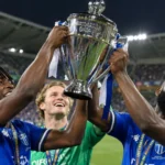 Drie voetballers van South Melbourne vieren met de Australia Cup op het veld.