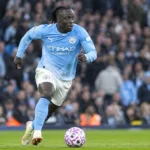 Jérémy Doku dribbelt met de bal in het lichtblauwe shirt van Manchester City.