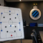 Lege tactische analysekamer van Club Brugge met een magnetisch voetbalbord en een clubplaquette aan de muur.