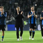 Coach en spelers van Club Brugge applaudisseren na afloop op het veld.
