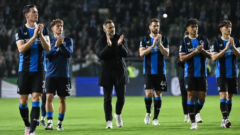 Coach en spelers van Club Brugge applaudisseren na afloop op het veld.