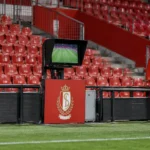 Lege rode tribunes van Standard naast een monitor voor videobeelden aan het veld.