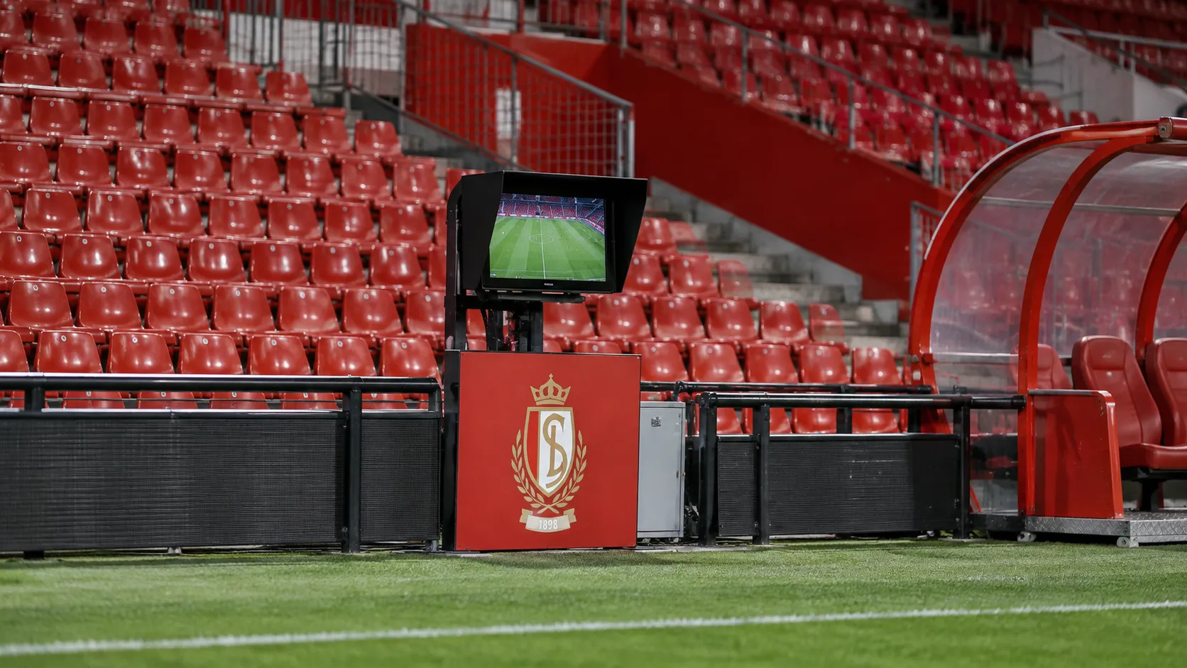 Lege rode tribunes van Standard naast een monitor voor videobeelden aan het veld.