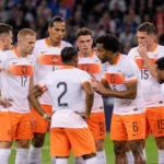 Nederlandse internationals verzamelen zich op het veld in witte en oranje tenues.