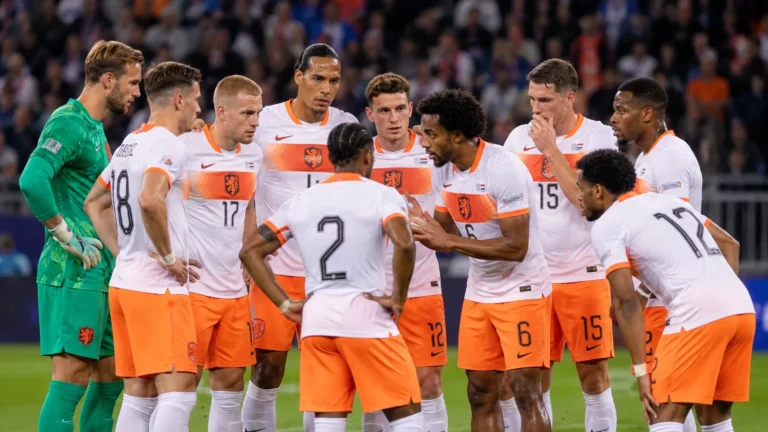 Nederlandse internationals verzamelen zich op het veld in witte en oranje tenues.
