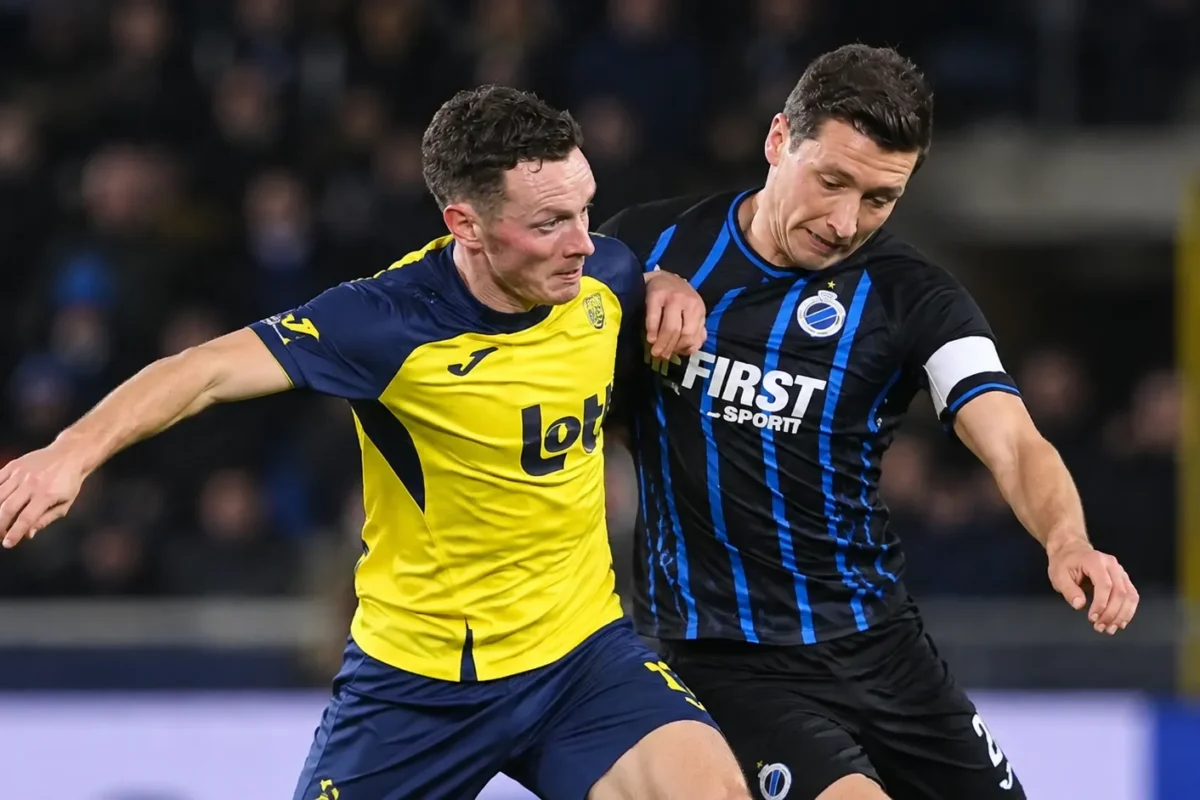 Twee voetballers strijden om positie tijdens een wedstrijd in de Belgische competitie.