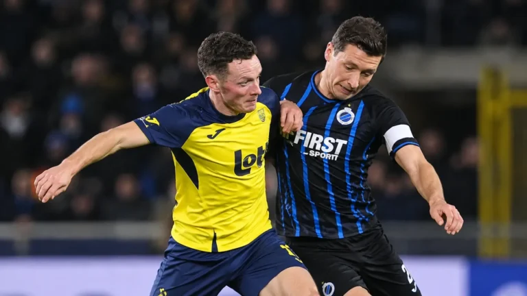 Twee voetballers strijden om positie tijdens een wedstrijd in de Belgische competitie.
