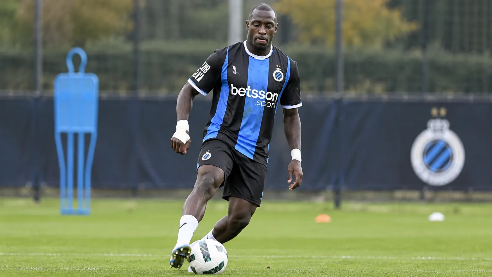 Een Club Brugge-speler in blauw-zwart tenue tijdens een opwarming op het veld.