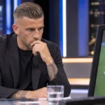 Toby Alderweireld aan een analysetafel in een televisiestudio terwijl hij voetbalbeelden bekijkt.