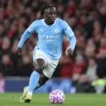 Jérémy Doku dribbelt met de bal in een lichtblauw Manchester City-tenue.