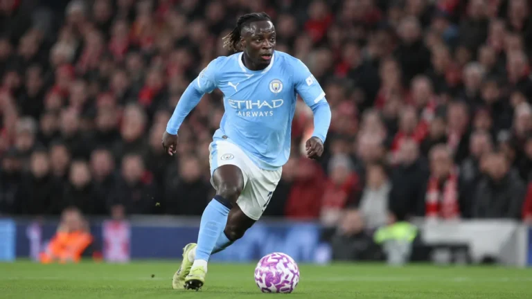 Jérémy Doku dribbelt met de bal in een lichtblauw Manchester City-tenue.