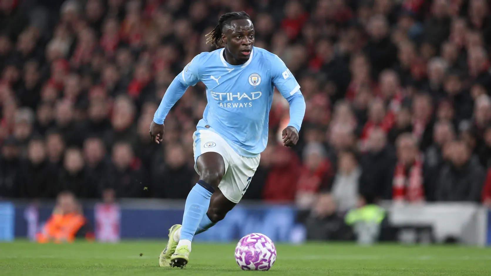 Jérémy Doku dribbelt met de bal in een lichtblauw Manchester City-tenue.