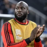 Romelu Lukaku in Belgisch trainingsshirt en geel hesje aan de zijlijn.