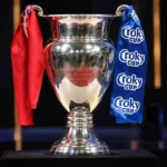 De zilveren Croky Cup-trofee met rode en blauwe linten op een donker podium.